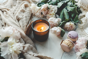 Burning candle, macarons and peonies, home aesthetics