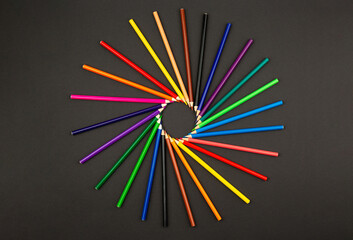 Colorfull pencils in form of circkleon black background. Top view. Graphick concept. All colors in a round. Color palette. Artist's painter's instruments. Colored pencils isolated on black background