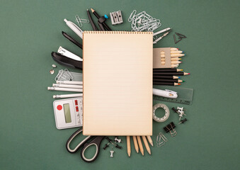 Mock-up Planning. Copy space. Stationery items around of notebook on dark green background. Back to school, banner with copy space. Student's or engineer's supplies. Office objects