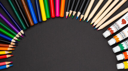 stationery items around of image on black background. Back to school background, banner with copy space. Student's or engineer's supplies. Office objects on dark background. Calculator, pencils, paint