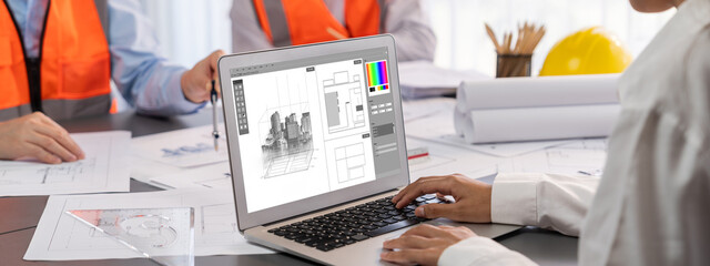 Engineer and architect working together brainstorming and designing blueprint using laptop working...