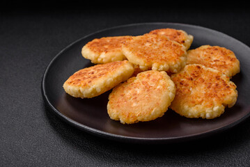 Delicious fresh cottage cheesecakes with raisins and vanilla on a black ceramic plate