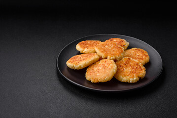Delicious fresh cottage cheesecakes with raisins and vanilla on a black ceramic plate