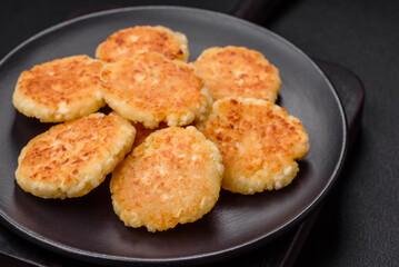 Delicious fresh cottage cheesecakes with raisins and vanilla on a black ceramic plate