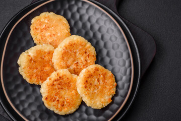 Delicious fresh cottage cheesecakes with raisins and vanilla on a black ceramic plate
