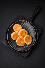 Delicious fresh cottage cheesecakes with raisins and vanilla on a black ceramic plate