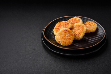 Delicious fresh cottage cheesecakes with raisins and vanilla on a black ceramic plate