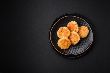 Delicious fresh cottage cheesecakes with raisins and vanilla on a black ceramic plate
