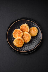 Delicious fresh cottage cheesecakes with raisins and vanilla on a black ceramic plate