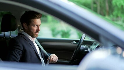 Man driver fastens the seat belt in the car before driving Businessman in suit taking care Protection of a person in vehicles. Compliance with safety rules for drive Road safety regulations concept