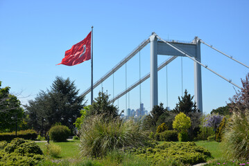 The Turkish flag is waving in the wind in a park overlooking the bridge over the Bosphorus and beautifully blooming sakura. Travel Istanbul background photo