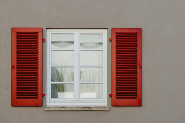 Italian windows on the grey wall facade with open red color classic shutters. window shutter wall europe