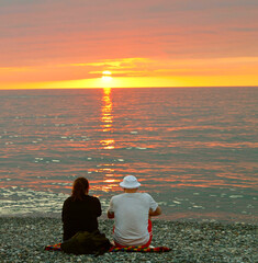 Silhouette of lover couple are enjoying beautiful nature sunset sun down. Batumi, GEORGIA. Black sea. Pebble shore, beach.