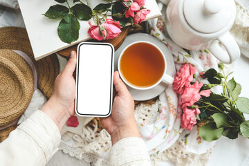 Phone in hands with an isolated screen on the background of a cup of tea