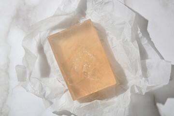 Natural bar soap for healthy skin and hair. Hydrating cleansing bar on crumpled package paper	