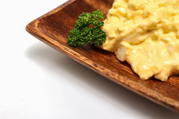 白背景の木製の皿に盛った卵サラダ