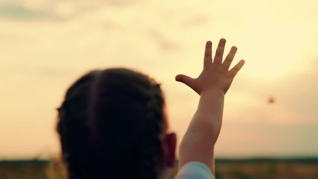 Hand of little girl at sunset. Sun between hands of kid girl. Happy child dreams stretches out his hand to sunset, summer park. Child dream hand to sun. Happy family on walk. Childs prayer outdoors