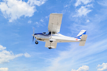Single engine ultralight plane flying in the blue sky with white clouds	