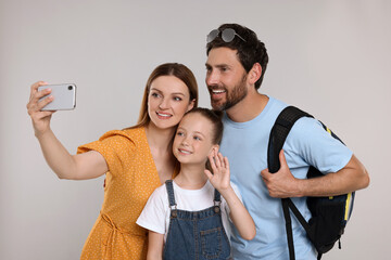 Happy family taking selfie on light grey background