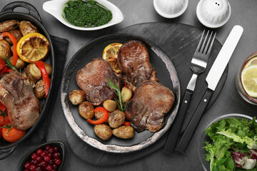 Tasty beef tongue pieces with potatoes and ingredients on grey table, flat lay