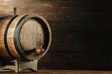 Wooden barrel with tap on table near wall. Space for text