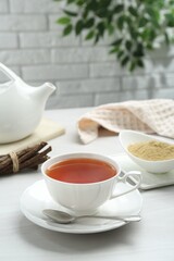 Aromatic licorice tea in cup served on white table