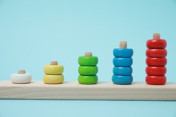 Stacking and counting game wooden pieces on light blue background. Educational toy for motor skills development