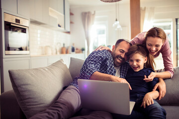 Young family using a laptop while sitting on the couch in the living room