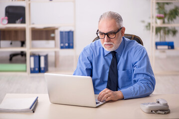 Fototapeta premium Old male employee working in the office
