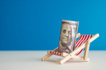 Happy US dollar bill banknote rest on wooden beach chair with blue background copy space in summer...