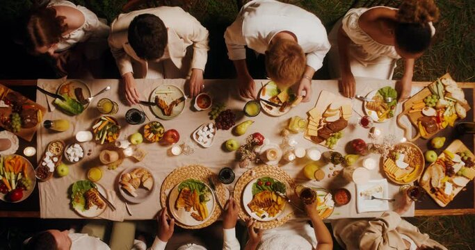 Top view of a beautifully laid festive table. Guests eat and talk while sitting at the table outdoor