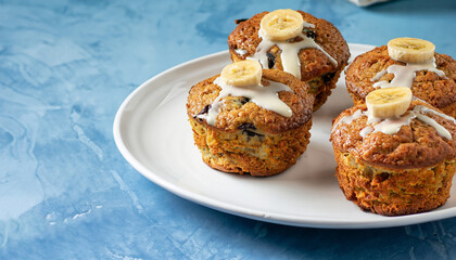 Healthy vegan oat muffins, apple and banana cakes with sour cream on a white plate Blue stone background