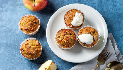 Obraz na płótnie Canvas Healthy vegan oat muffins, apple and banana cakes with sour cream on a white plate Blue stone background