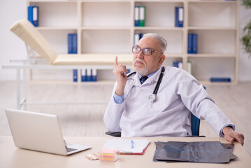 Old male doctor working in the clinic