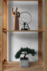 Glowing lamp with decor and bonsai on shelves in room