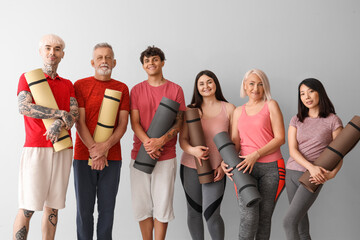 Obraz premium Group of sporty people with fitness mats on light background