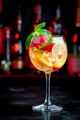 Rose sangria summer alcoholic drink with pink wine, peach, orange, lime and ice. Black bar counter...