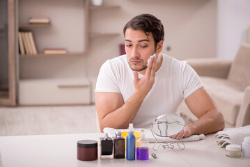 Young man shaving face at home