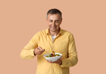 Mature man with prepared vegetables on beige background
