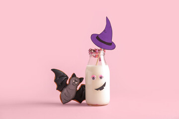 Bottle of milk, tasty cookie and hat made of paper for Halloween on pink background