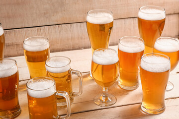 Glasses and mugs of cold beer on light wooden background. Oktoberfest celebration