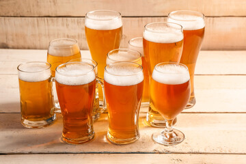 Glasses and mugs of cold beer on light wooden background. Oktoberfest celebration