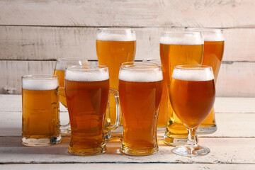 Glasses and mugs of cold beer on light wooden background. Oktoberfest celebration