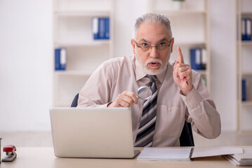 Fototapeta premium Old male employee working in the office