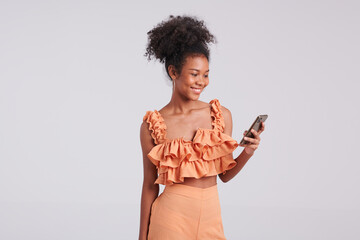 A digital fashionista, a black girl in an orange shirt takes charge of her studio shoot, using her...
