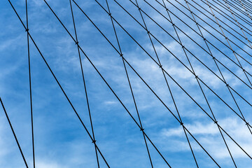 Steel cables of a bridge in a blue sky background - 623945786