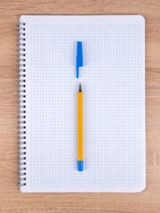 A blue pen lies on a notebook in a box. The pen is ready to go