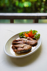 deep fried organic fish or mackerel with fish sauce 2 pieces and vegetable lettuce carrot in white plate on table and green garden background for seafood and protein food to delicious cuisine vertical