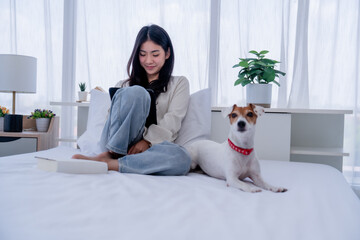 Asian Woman Working from the Comfort of Her Bedroom with Her Adorable Pet by Her Side
