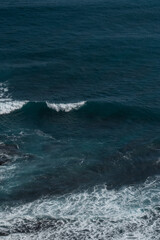 The waves of the ocean water meet with underwater pointed rocks